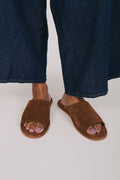 Brown sandals worn with blue jeans on a white background