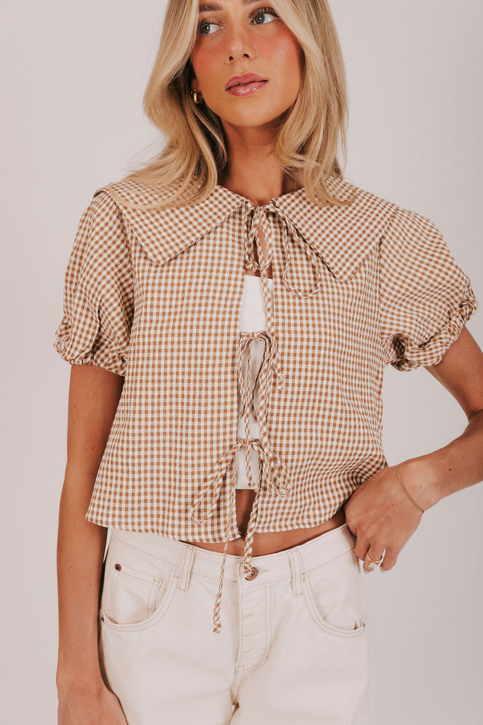 gingham blouse with open front and tied bow closure. Short puff sleeves
