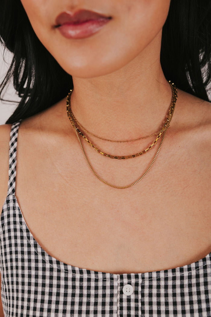 stainless steel gold colored necklace with three layers of box chains and an adjustable lobster clasp
