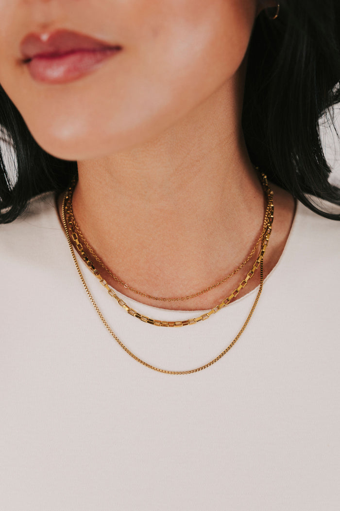 stainless steel gold colored necklace with three layers of box chains and an adjustable lobster clasp