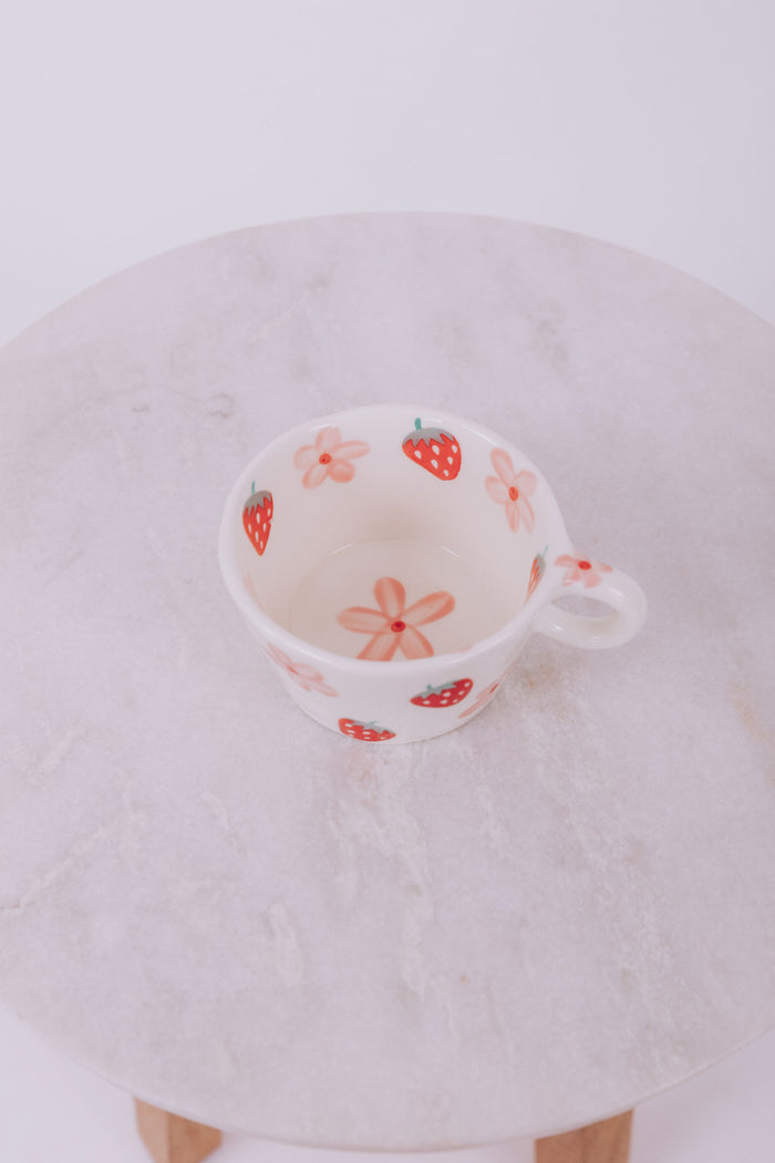 Ceramic mug with strawberry and flower pattern with a white background