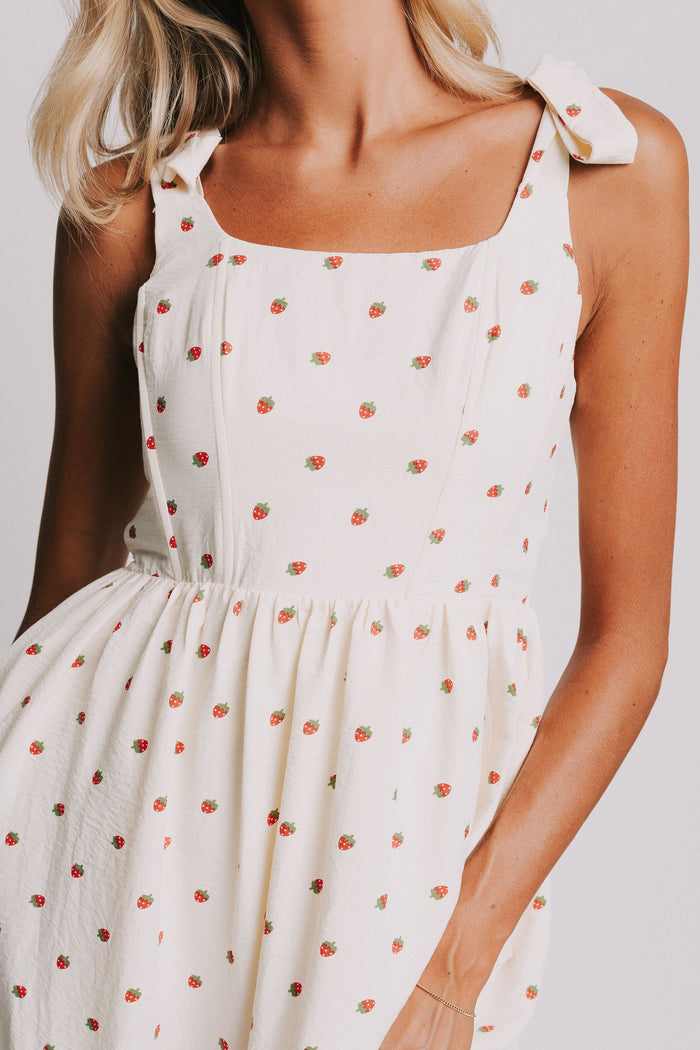 cream midi dress with strawberry print and bows on shoulders close