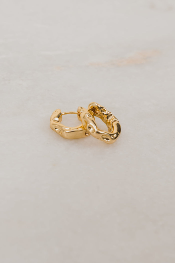 Gold hoop earrings on a light gray background