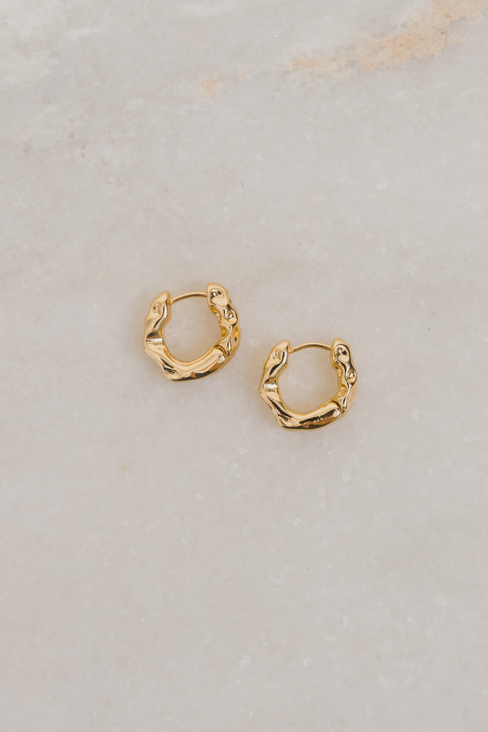 Gold hoop earrings on a light gray background