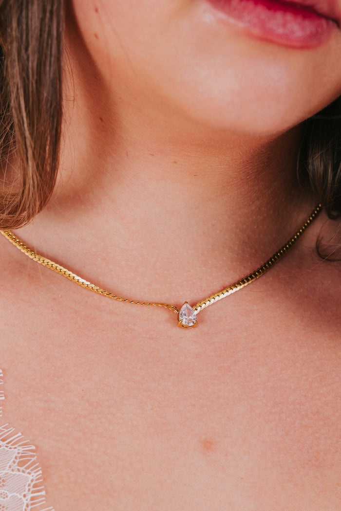 Gold necklace with a herringbone chain and cubic zirconia tear drop pendant