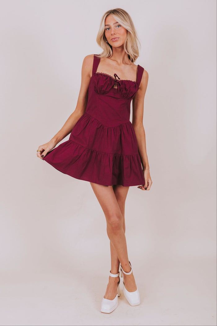 Woman wearing a burgundy dress against a plain background