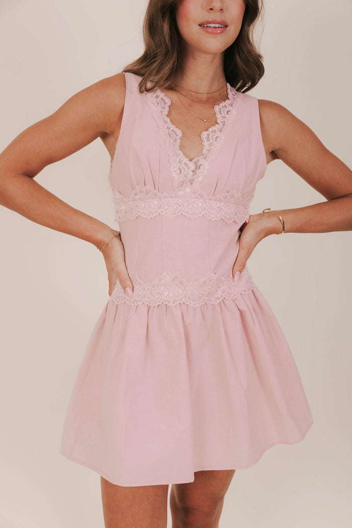 Pink sleeveless dress with a corset inspired bodice and lace trim at a mini length