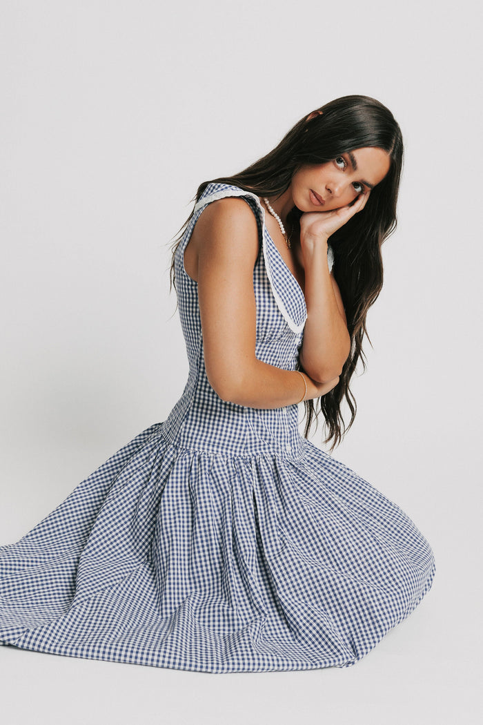 sleeveless blue and white gingham drop waist dress with collar pose