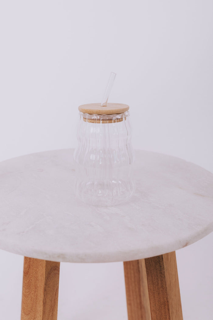 Wavy designed glass cup with wood lid and matching glass straw.