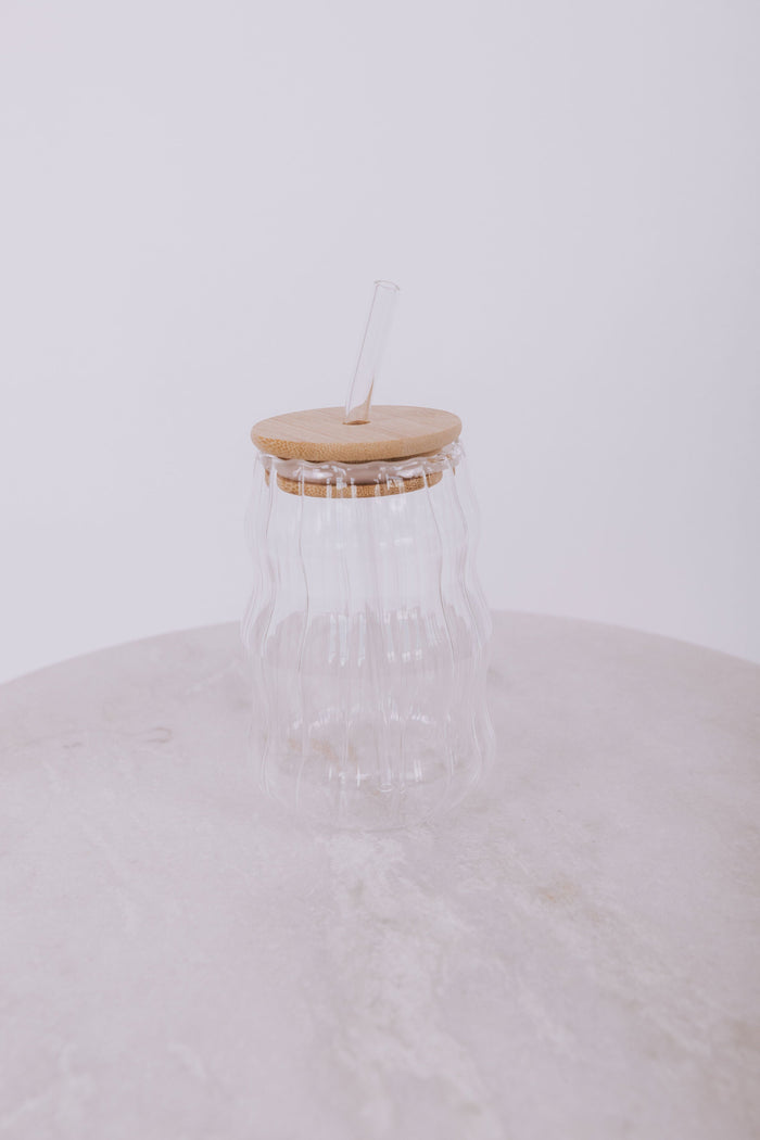 Wavy designed glass cup with wood lid and matching glass straw.