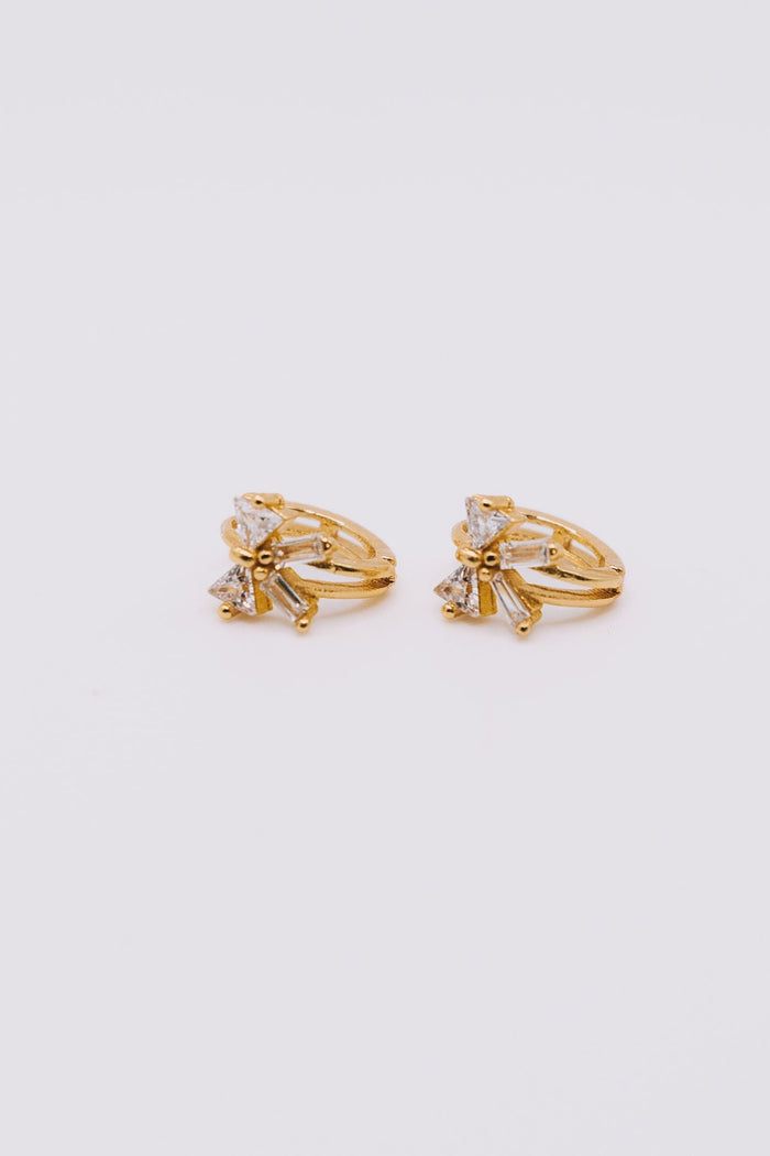 Pair of gold earrings with small diamonds on a light gray background