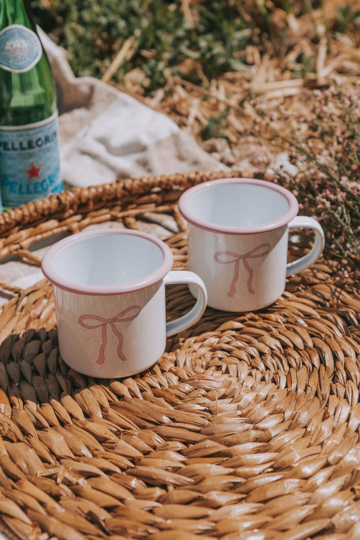 White camper mug with pink rim and pink bow design.